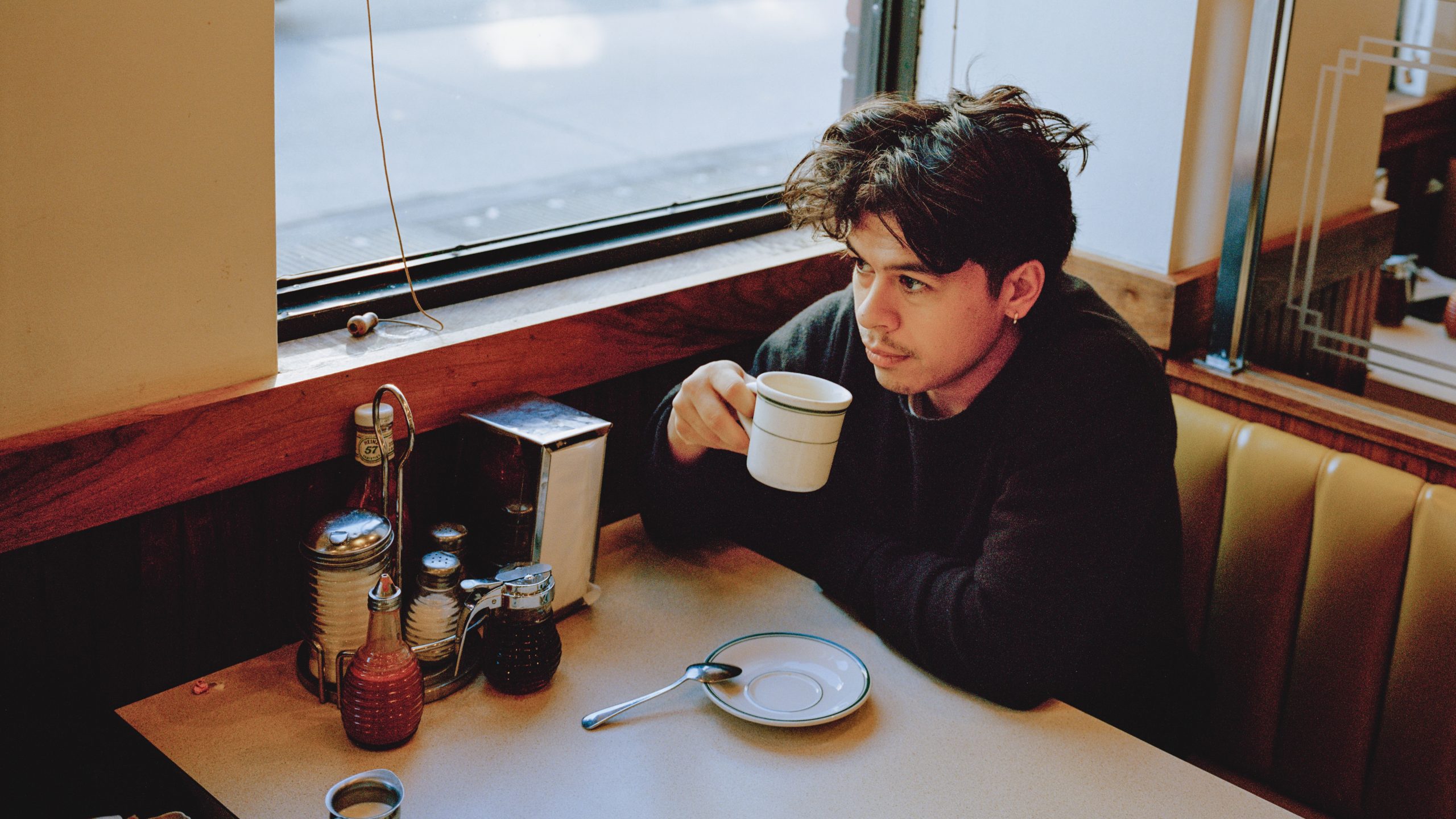 Will Matsuda ’15 sits at a diner booth with a cup of coffee in hand.