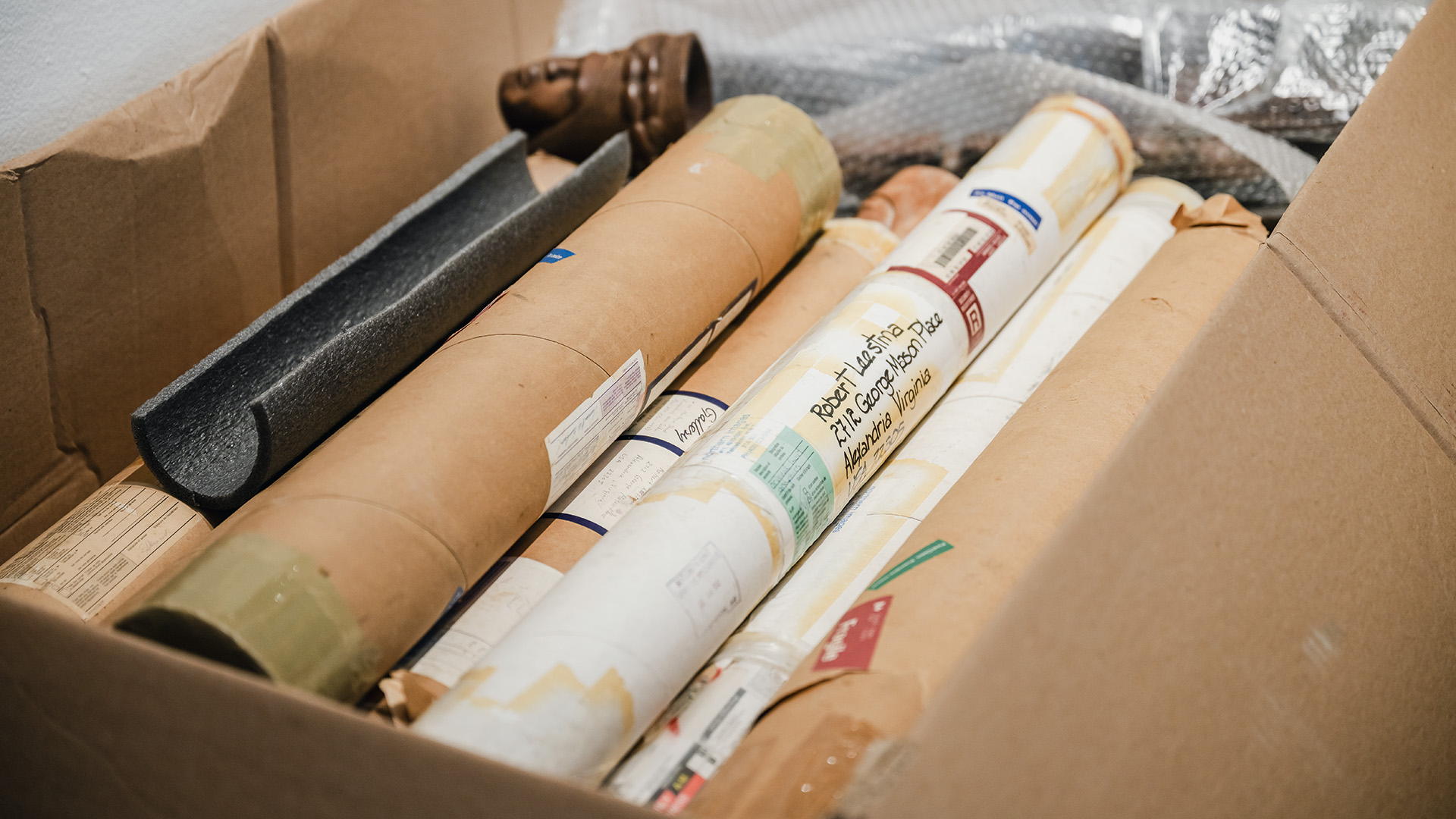 Box containing dozens of prints wrapped up in packing tubes