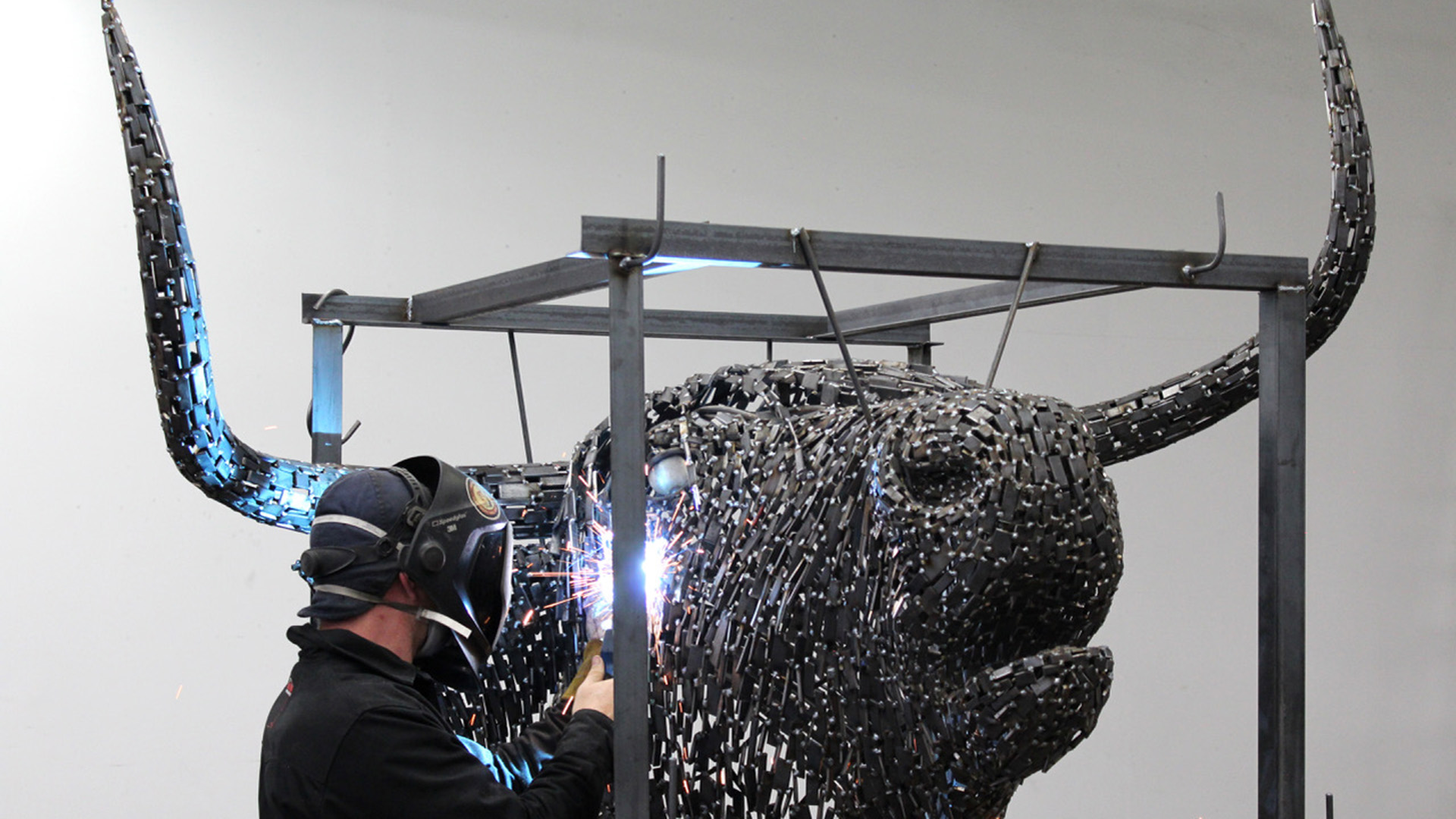 A sculptor works on the metal head of Macalester's new Coo sculpture.