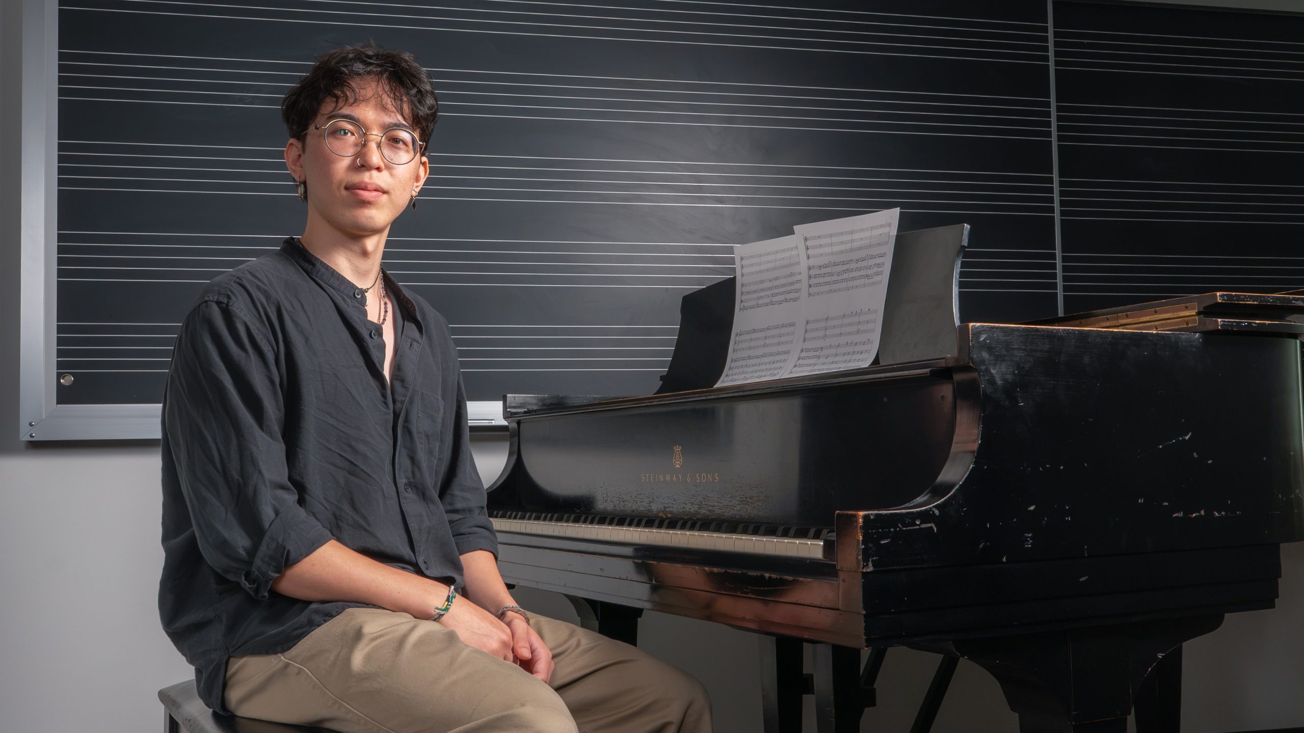Music major Max Chang ’27 poses for a photo in front of a grand piano.