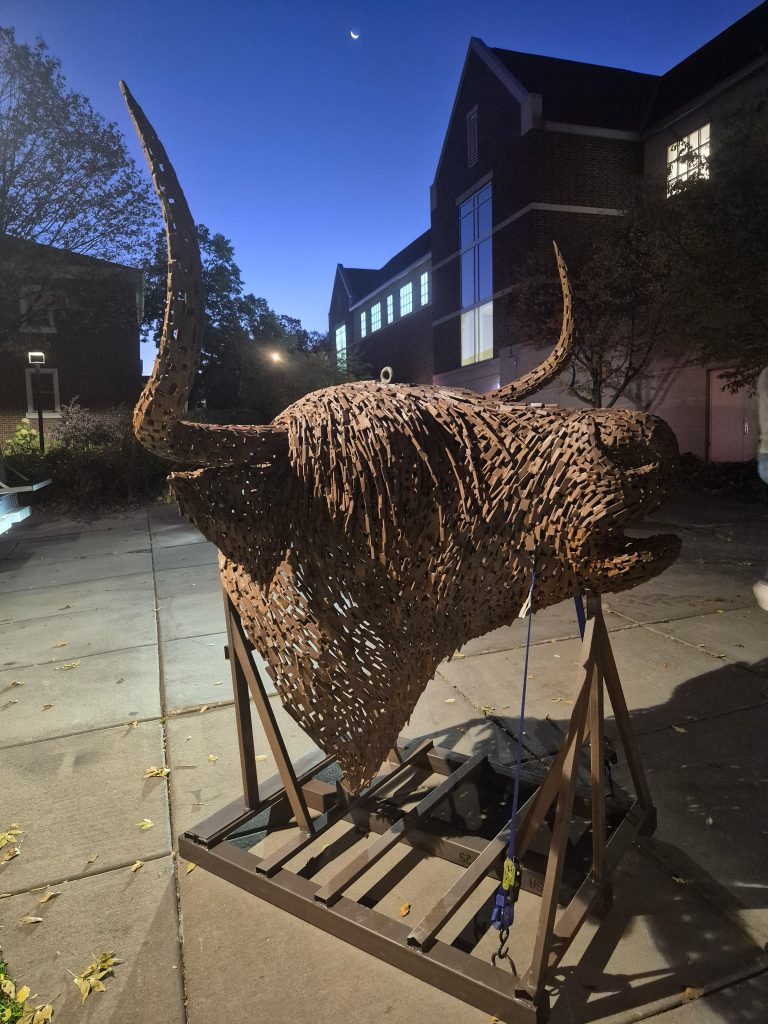 The head section of a new sculpture, Coo, waits on a campus sidewalk to be installed.