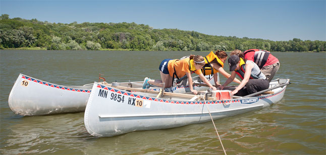 Four students in two canoes on the Mississippi River