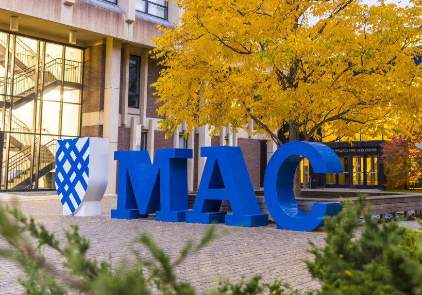 The blue Mac letters sculpture sits outside the Janet Wallace Fine Arts building during the fall.
