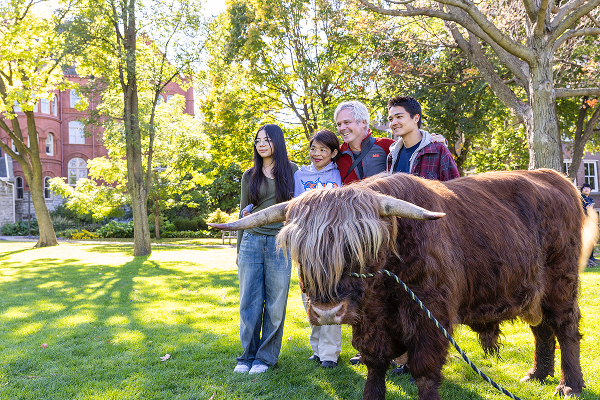 A family poses beside a Highland Coo at Mac Fest.