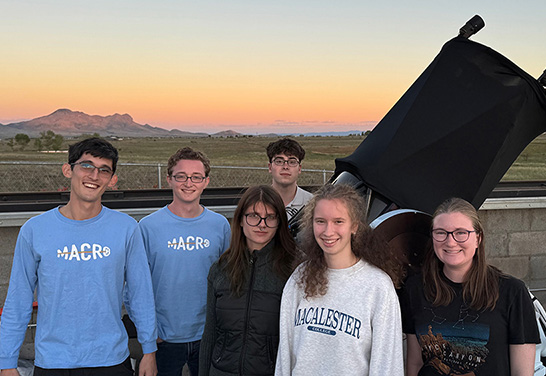 Six students stand beside a large telescope