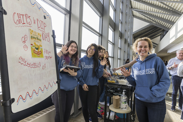 Psychology students and faculty smile next to a whiteboard reading Chips and Dip Day