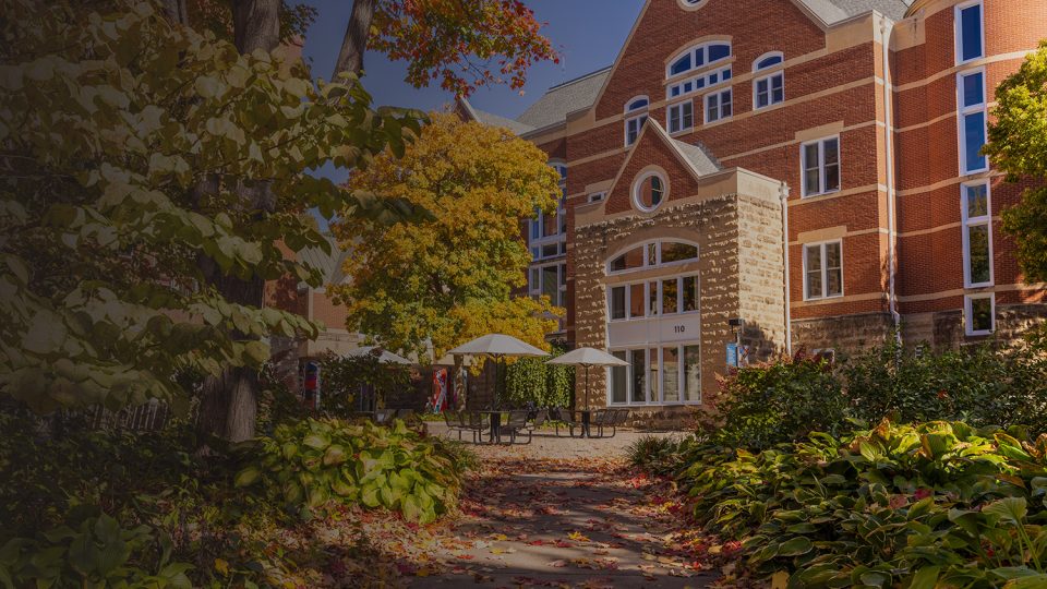 Leaves start to change color on trees and bushes outside the Macalester library and Old Main.