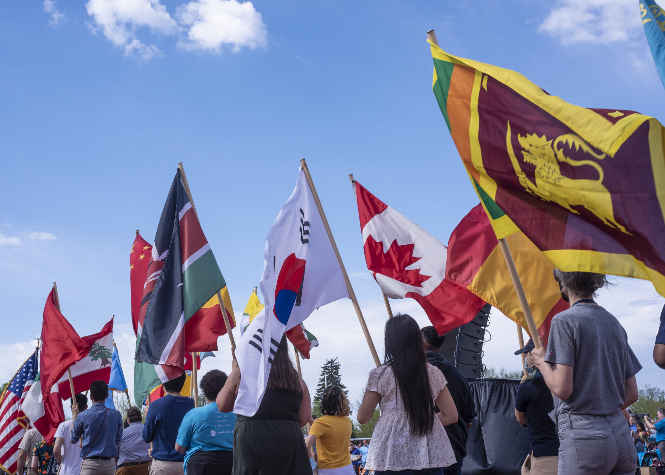 A line of students carry flags of the world across campus.