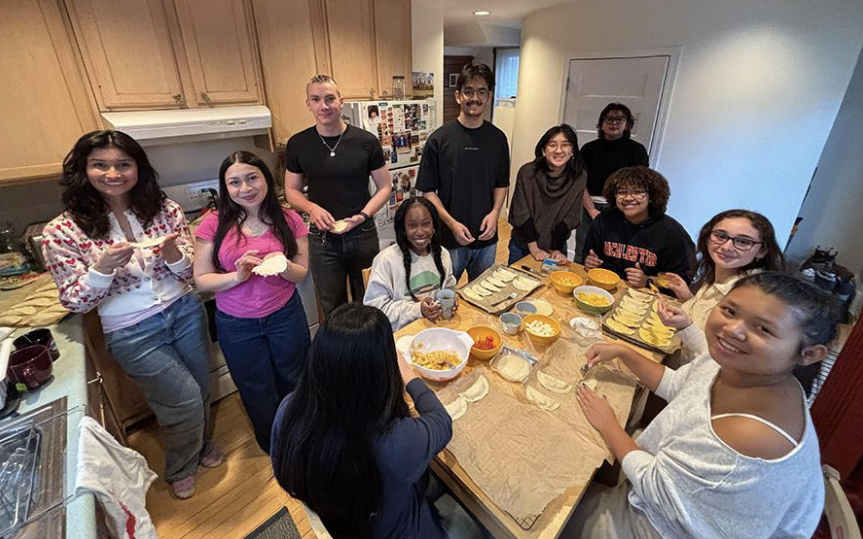 Professor Erika Busse-Cardenas and sociology students gather around a kitchen table with homemade empanadas.
