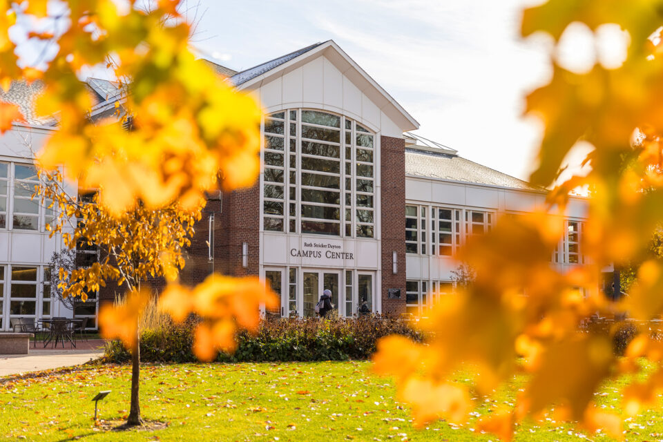 Orange fall leaves shine in front of the Campus Center.