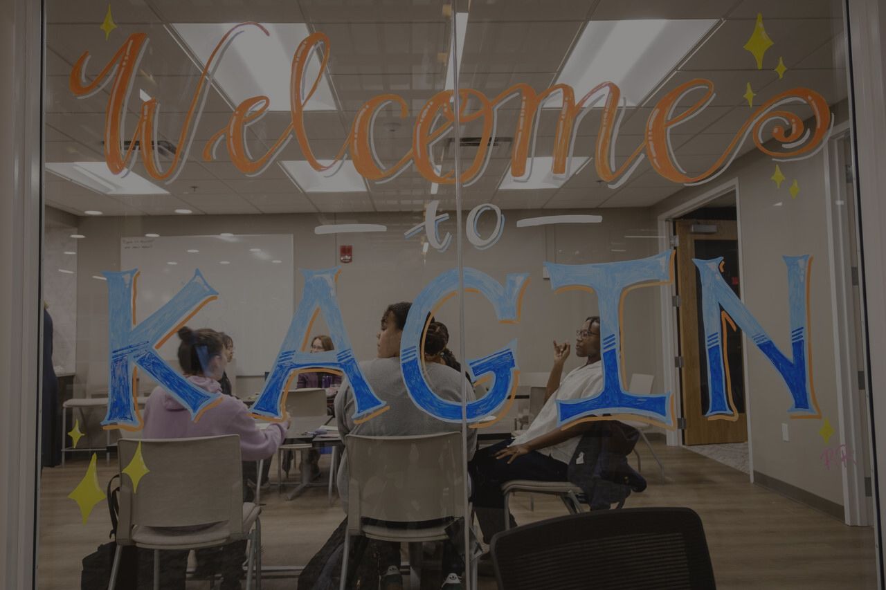 Welcome to Kagin is written on a glass wall in blue and orange letters.