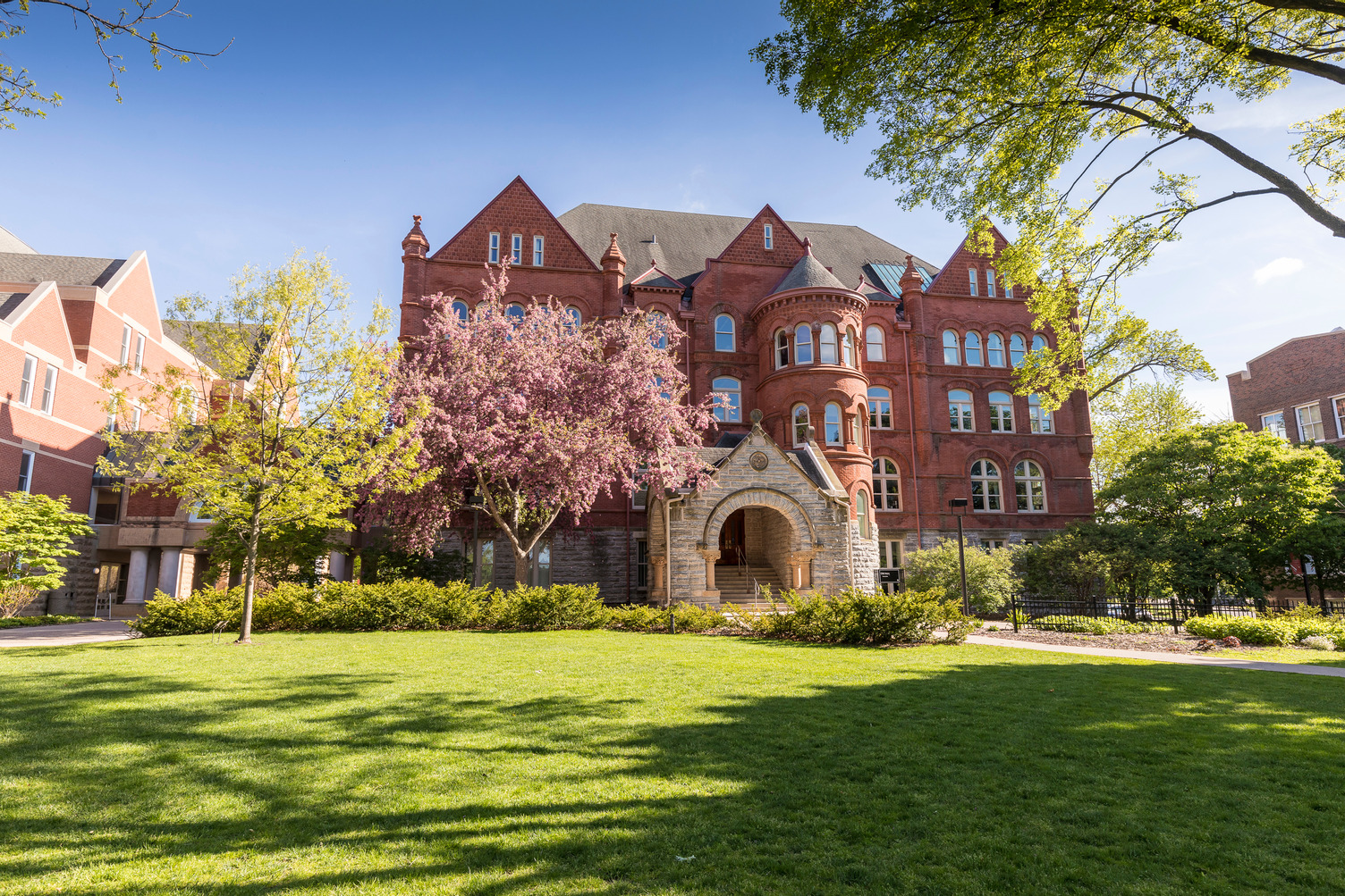 Old Main in the springtime, surrounded by flowering trees and a lush green lawn.