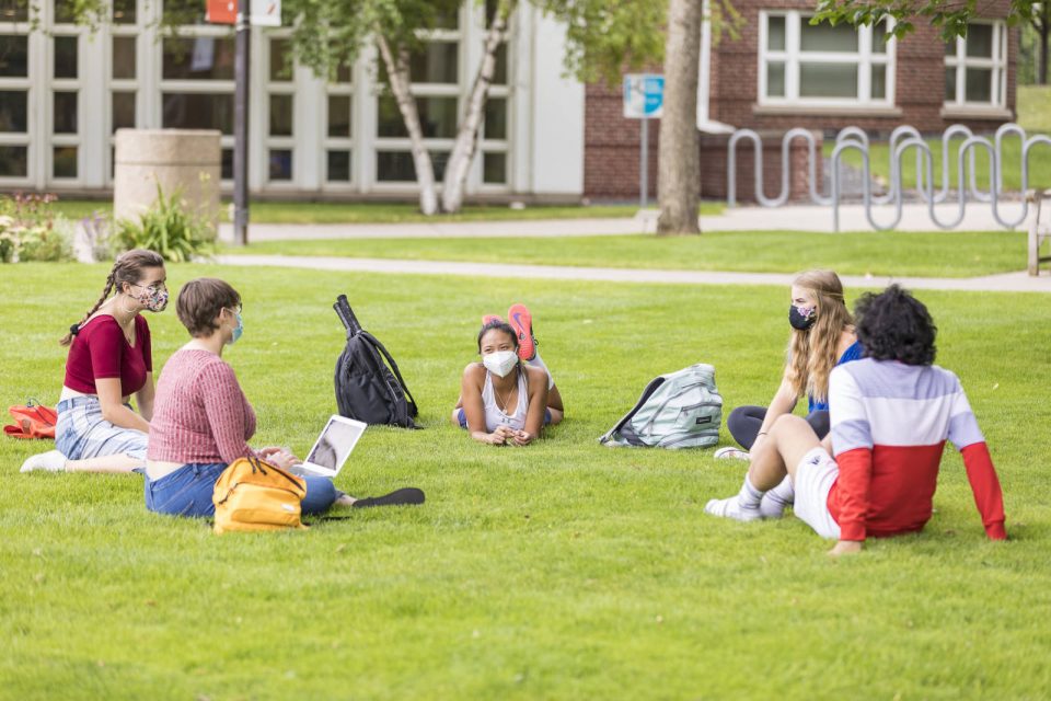 Macalester students in sitting on the lawn in a circle