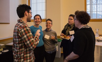 Alumni and faculty talk and laugh around a table