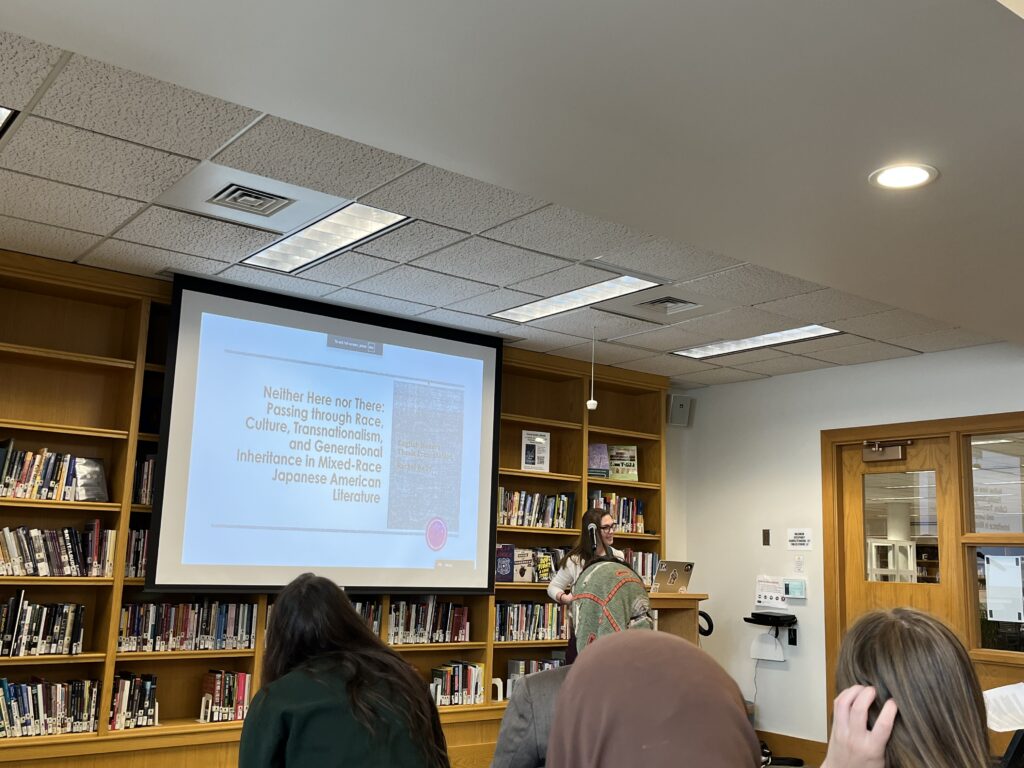 Rachel Kelly '25 presenting her Honors titled "Neither here Nor There" to a crowd of people.
