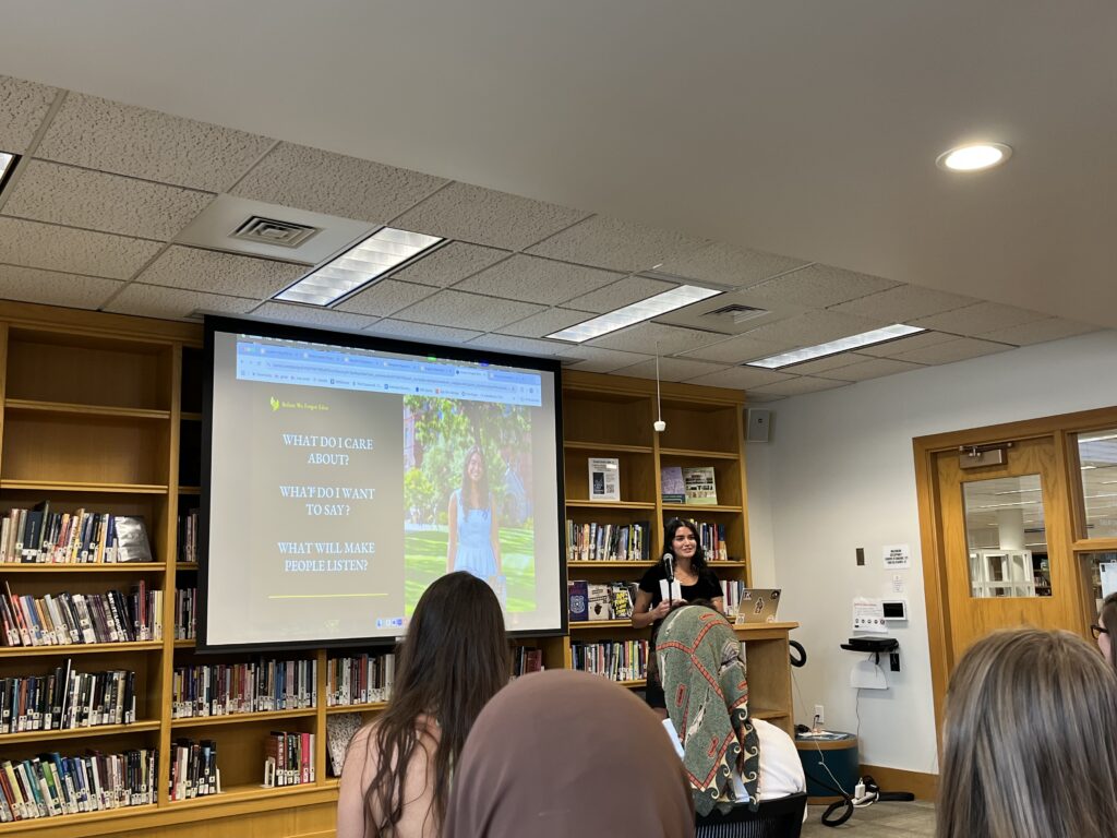 Sofia Vaz '25 presenting her Honors with slide asking questions about what she cares about to a crowd of people. 