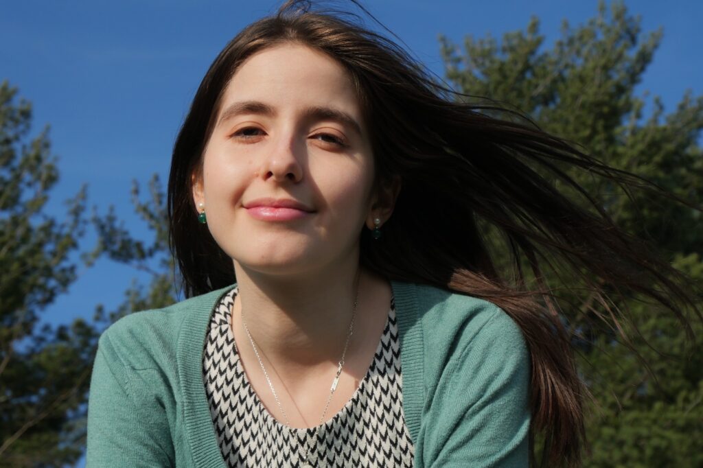 Miriam Ruiz looking at camera with trees and the sky behind her 