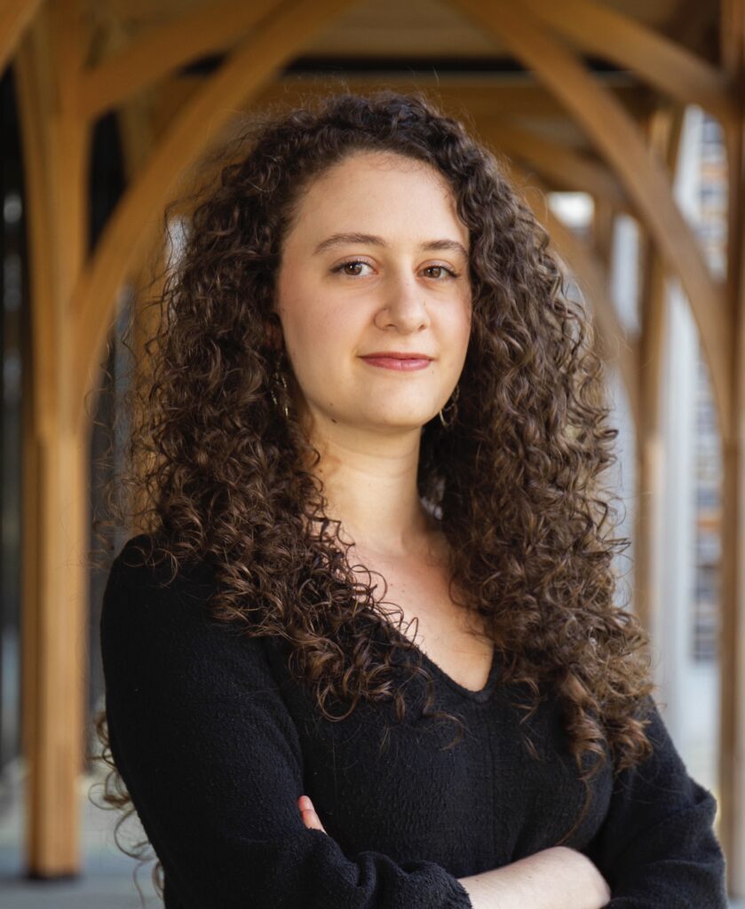 Zeena Yasmine Fuleihan poses for a headshot underneath a wooden archway