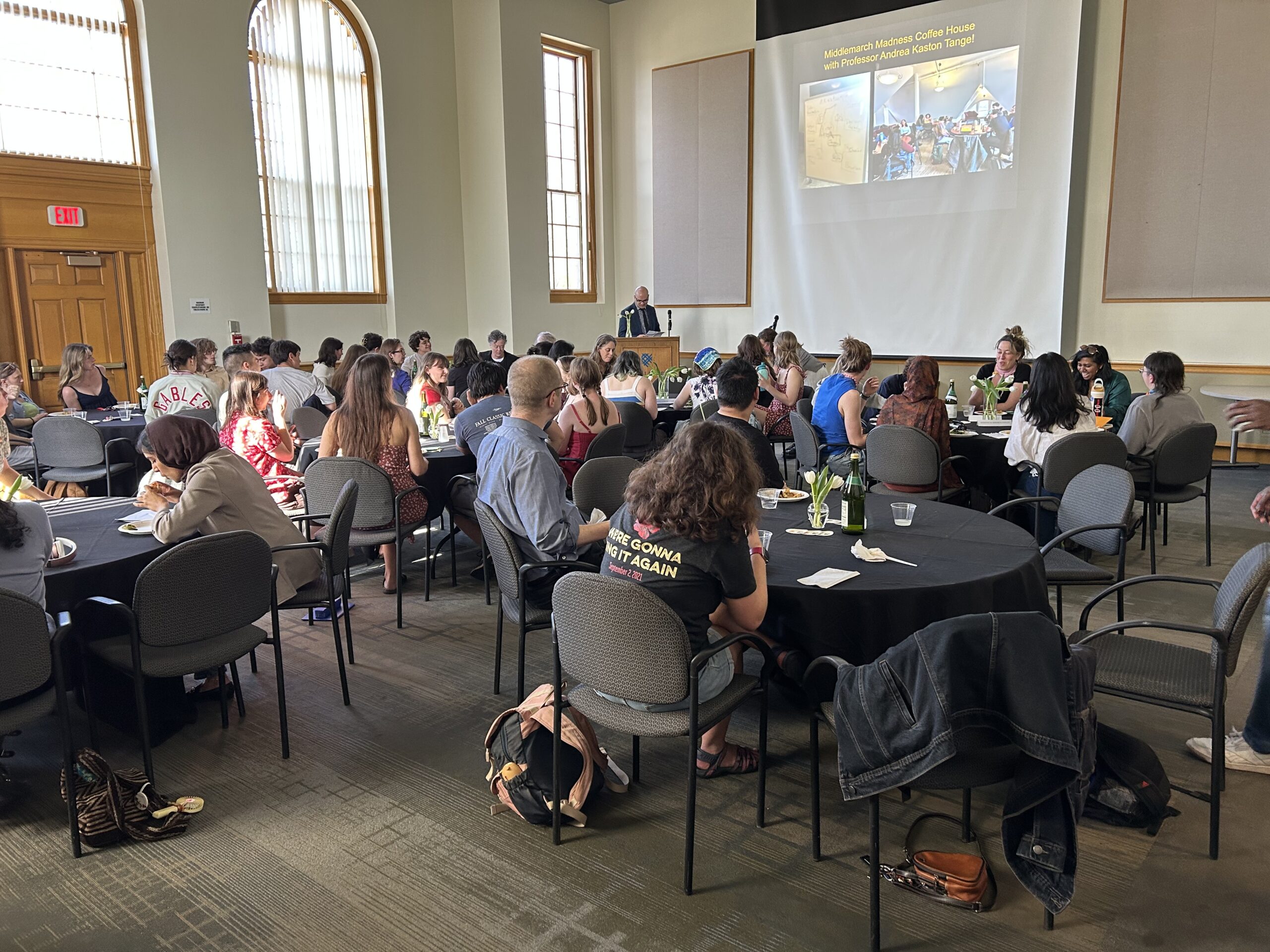 Tables of English students and staff sit and celebrate with sparkling juice in the Weyerhaeuser Board room
