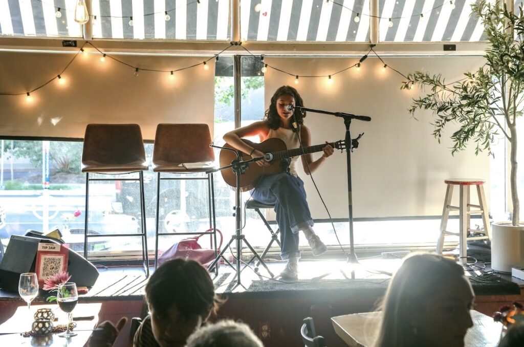 Maria sings and plays guitar on stage.