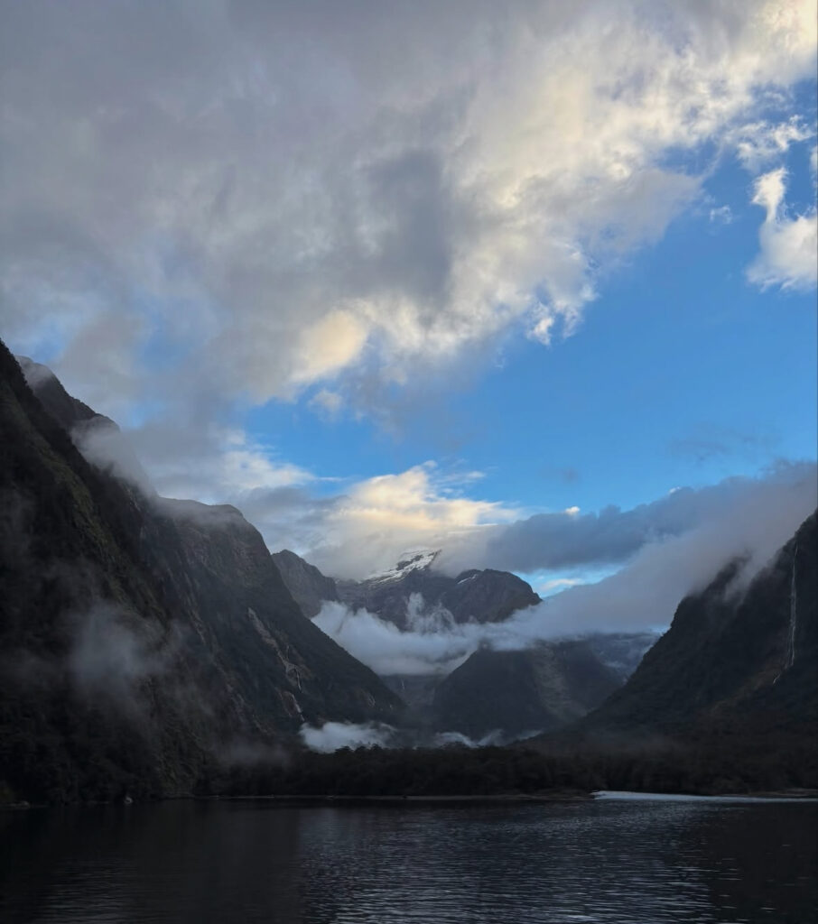Mountains are shrouded in low-hanging clouds in front of a lake