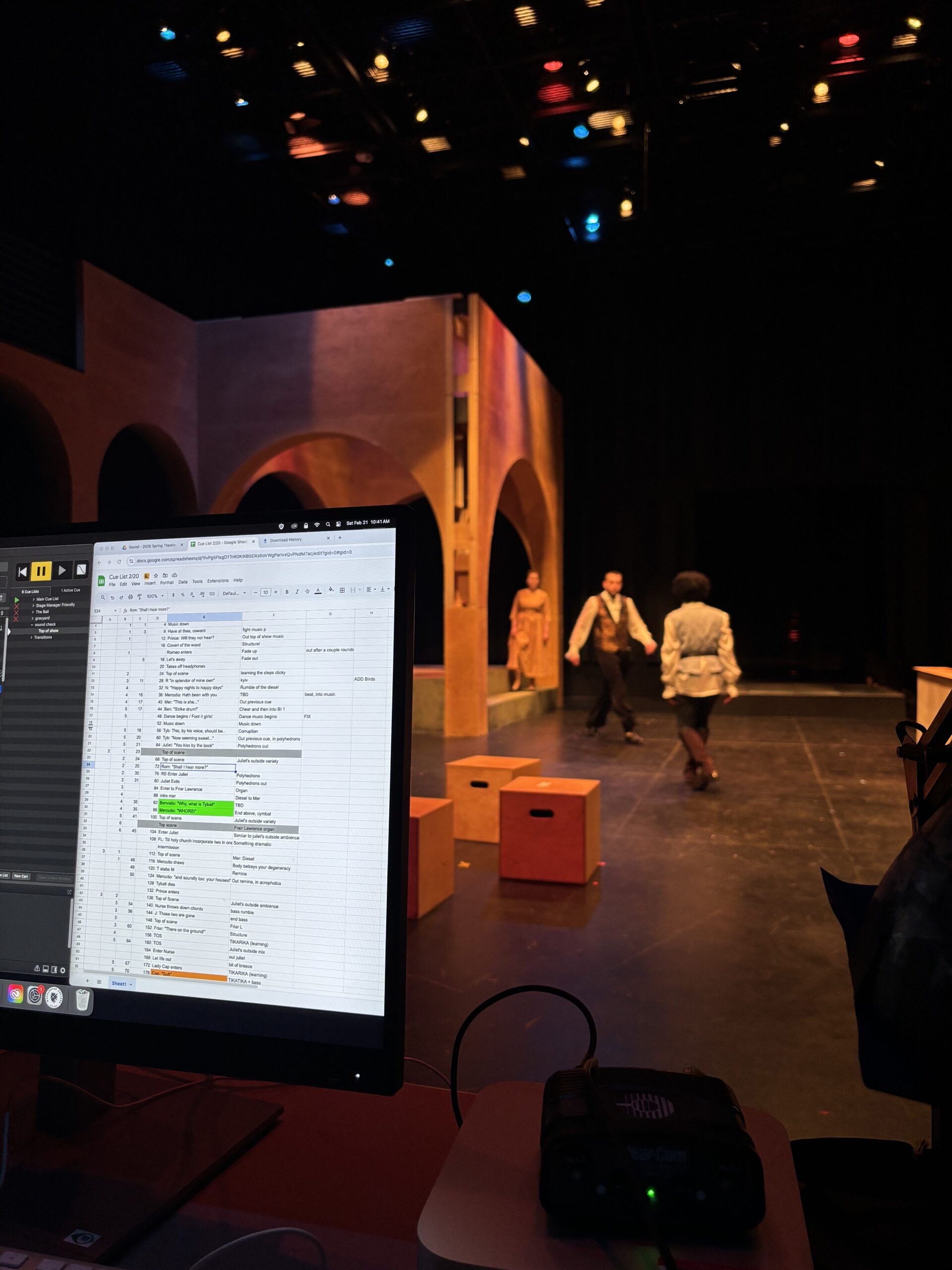 Backstage perspective of A Romeo and Juliet Experience shows a screen with sound cues while three actors move around the stage.