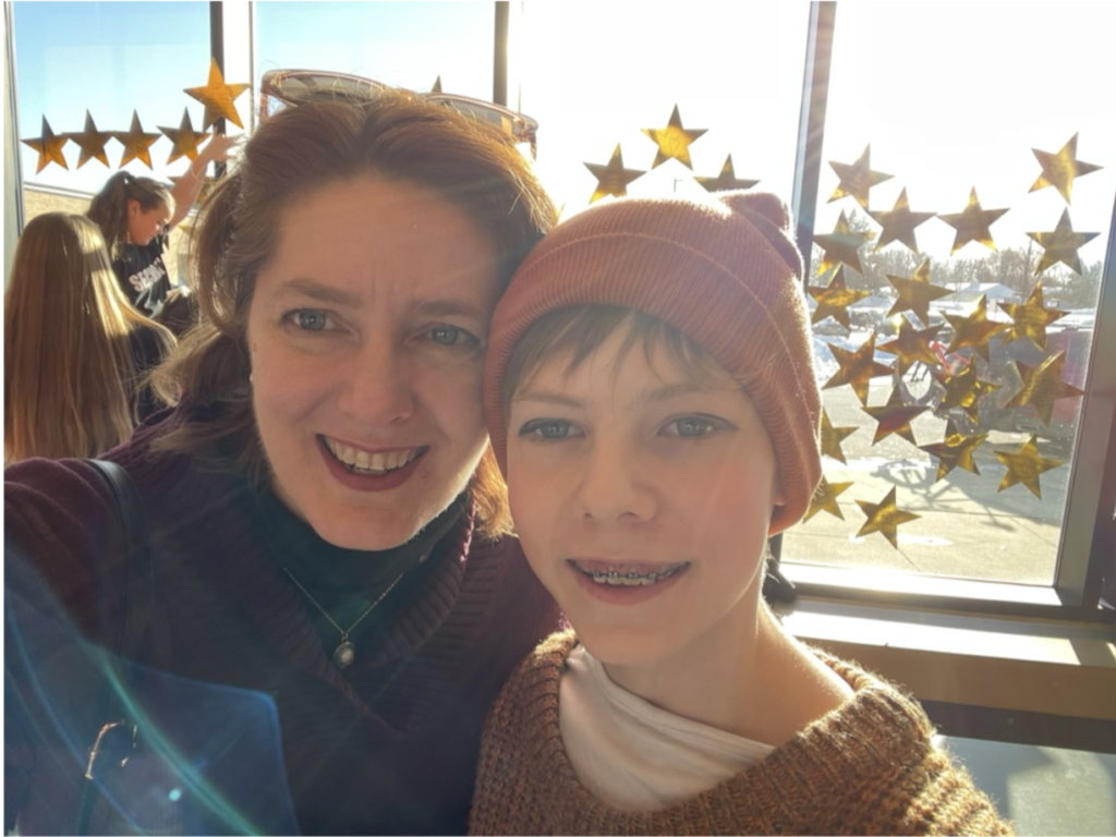 Selfie of Prof Sheldon and her child in front of a window filled with gold stars.