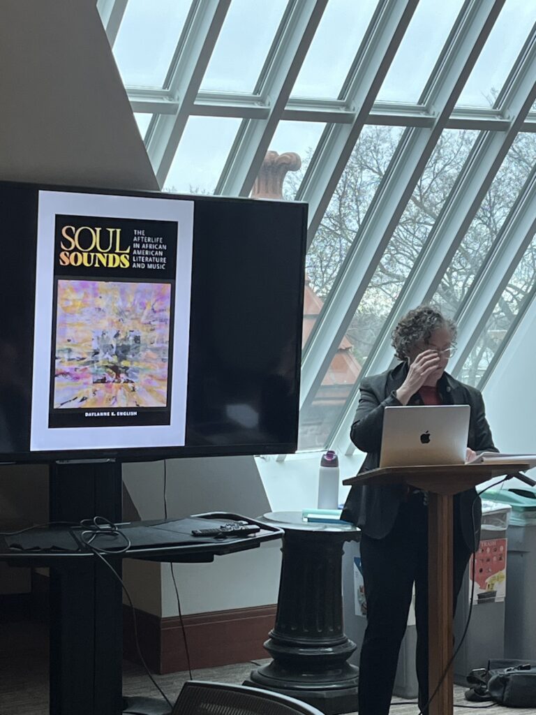 Professor English standing next to an image of her new book, Soul Sounds.