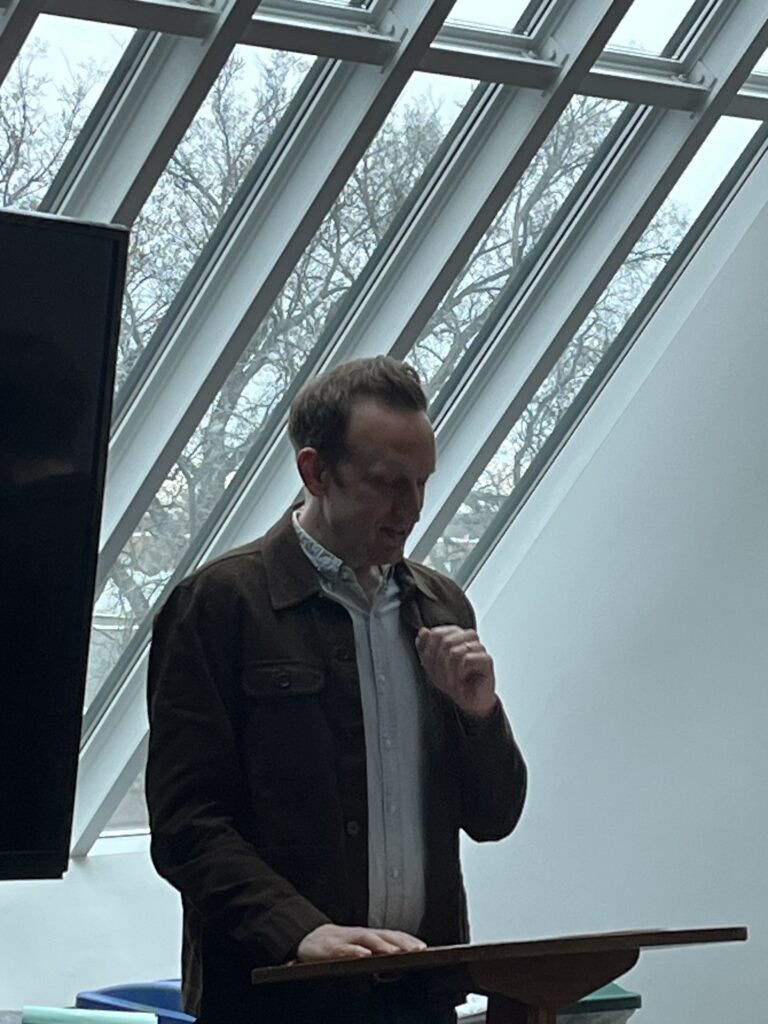 Professor Bognanni standing and reading from his manuscript.