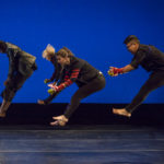 Several dancers jump in a V position