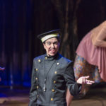 Actor in a police costume gestures off stage