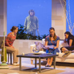Three actors sit around a living room set