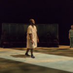 Actor wearing a hospital ground stands on stage