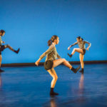 Three dancers kick up a leg on stage