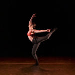 Dancer stretches a leg backwards on stage