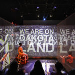 Letters|Home projection reads "We are on Dakota Land"