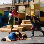 Three actors perform a mock fight on stage