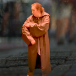 Actor in brown cloak stands on stage