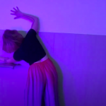 Performer stretching against a bathroom wall