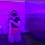 Performer kneeling next to a public toilet