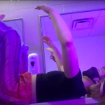Performer laying with arms and legs outstretched on a bathroom counter