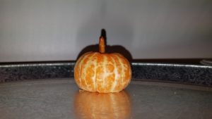 An orange made to look like a small pumpkin