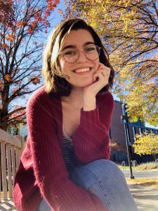 Becca Lewis '21 sitting on the Macalester college campus under autumn trees