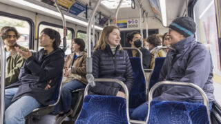 Professor and student sit next to each other and talk on Metro Transit during a recent trip in the Twin Cities