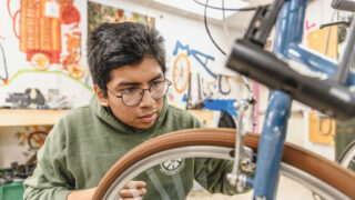A student fixes a bike wheel