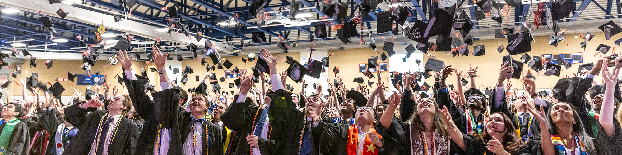 Graduates toss their caps at the end of a commencement ceremony.