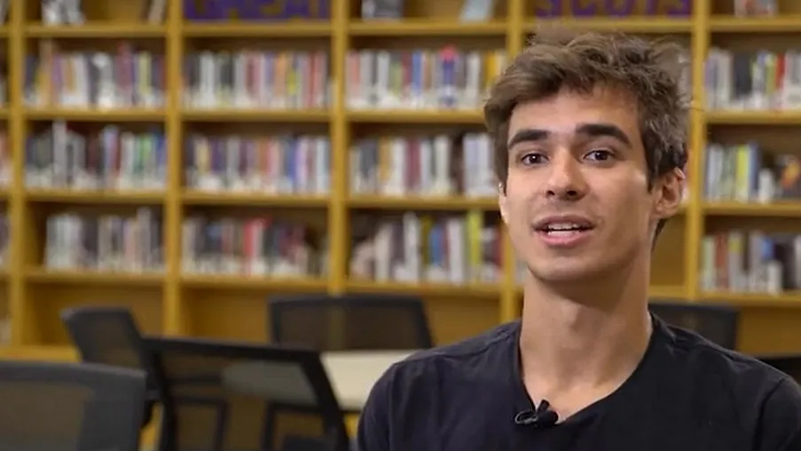 A student is interviewed in the library.