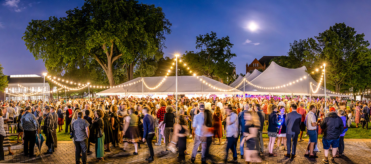 Alumni gather under a white tent on the Great Lawn for a party.