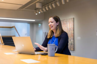 Admissions counselor Sarah Paulsen sits in front of a laptop, chatting to someone virtually.