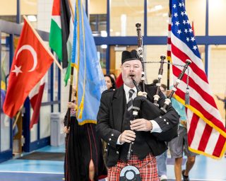Bagpiper leads a procession of international flags